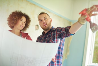 Female holding architectural plans discussing kitchen renovation with a contractor