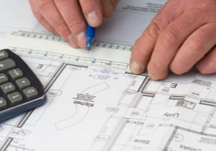 Hands holding down an architectural drawing of a kitchen addition